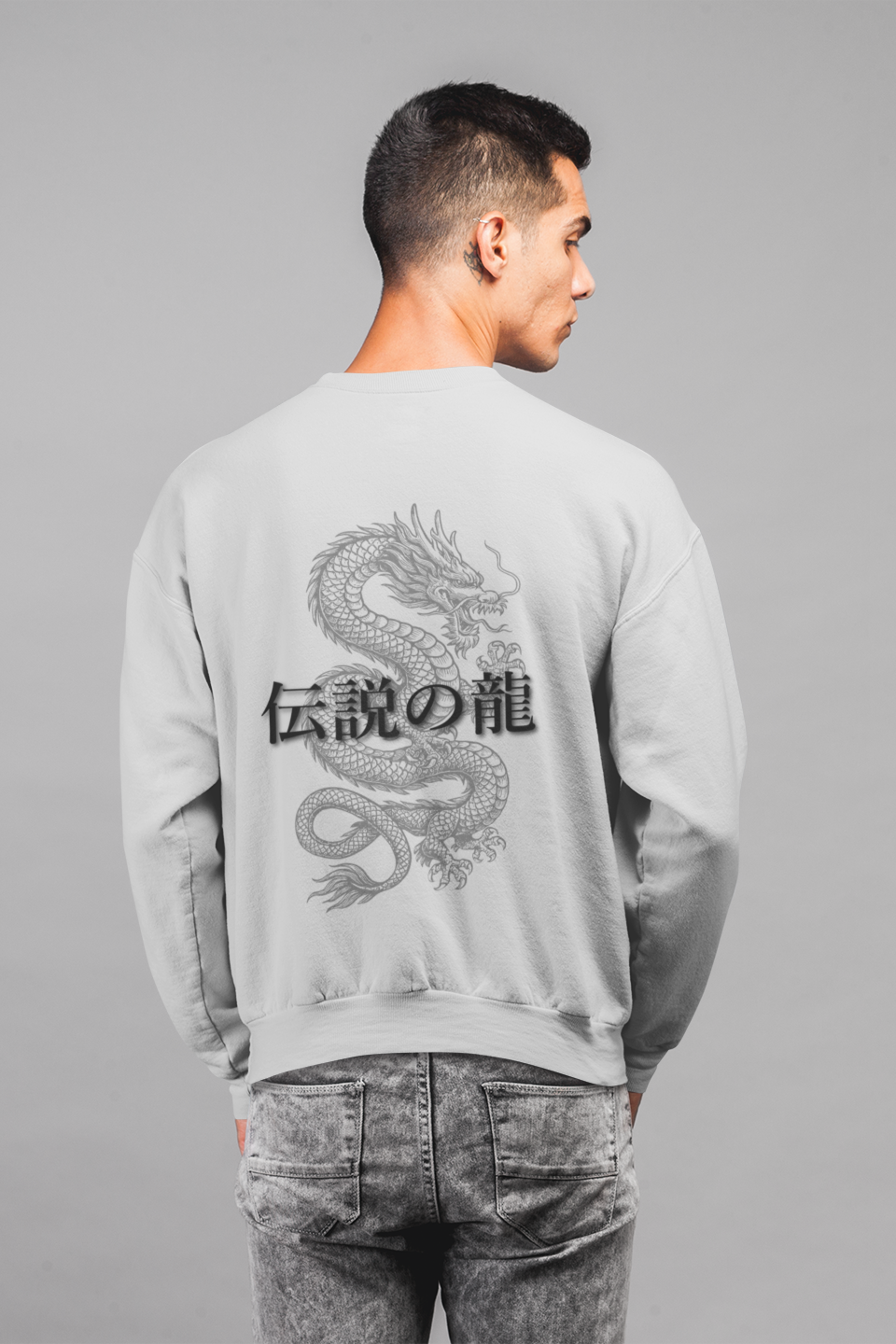 Man wearing a gray sweatshirt with a dragon design on the back against a gray background