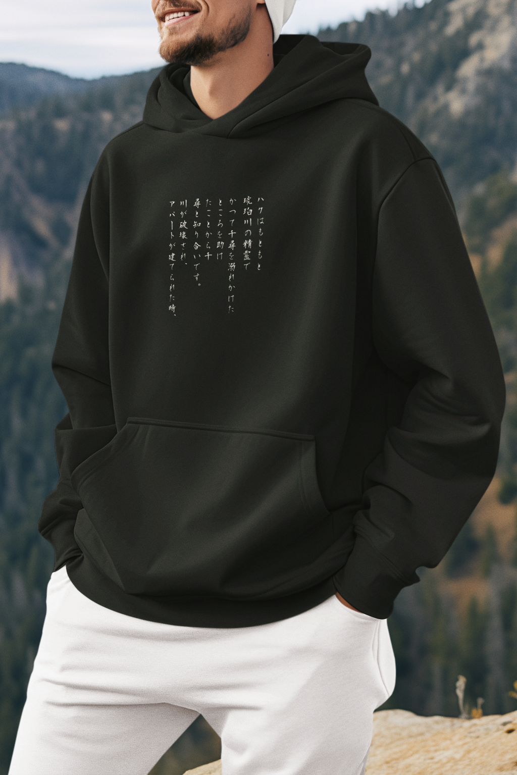 Person wearing a black hoodie with text in a mountainous landscape